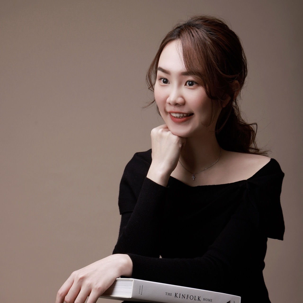 王彥婷 Tina 坐姿肖像，雙手扶著一本書