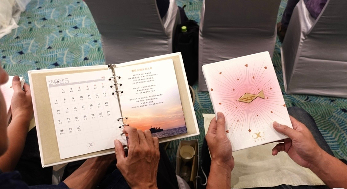 雙手翻開週年紀念冊，內頁呈現月曆與祝福文字
